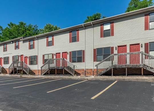 A parking lot in front of a building with red doors.