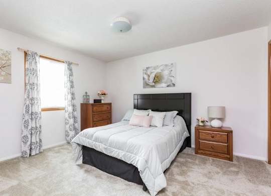 A bedroom with a large bed, nightstands, and a painting on the wall.