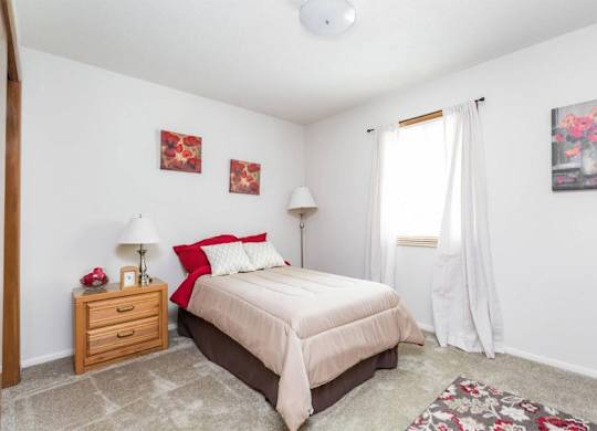 A bedroom with a bed, nightstand, and two pictures on the wall.