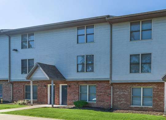 A two-story residential building with a brick facade and a grey siding.
