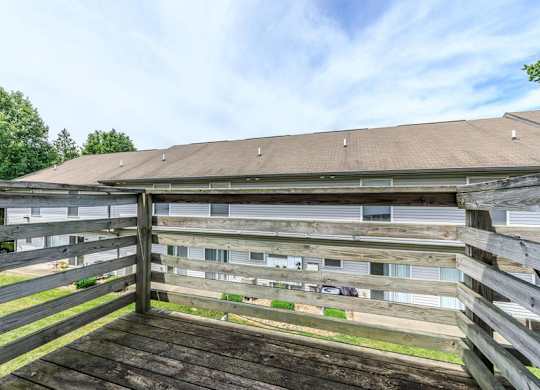 A wooden deck with a slatted fence and a building in the background.