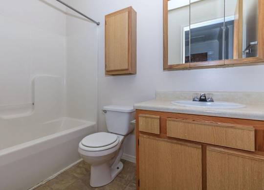 A white toilet sits in a bathroom next to a bathtub and a sink.