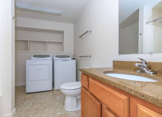 A bathroom with a toilet, sink, and cabinets.