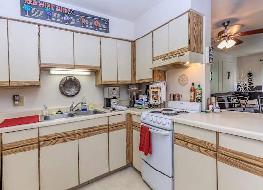 A kitchen with a white stove top oven and wooden cabinets.