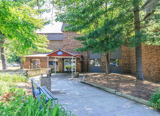 A building with a red roof and a sign that says "Chapel" is surrounded by trees and plants.