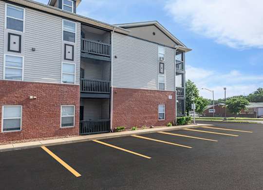 A parking lot in front of a multi-story apartment building.