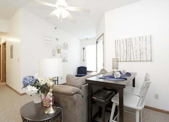 A living room with a couch, chair, dining table, and a painting on the wall.