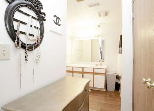 A bathroom with a mirror, a wooden vanity, and a wooden door.