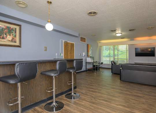 A bar area with black stools and a wooden counter.