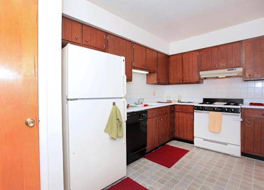 A kitchen with a white refrigerator and brown cabinets.
