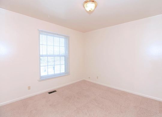 A room with a window and a carpeted floor.