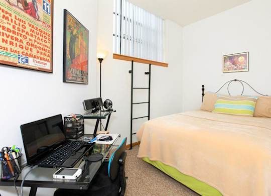A bedroom with a bed, desk, and a poster on the wall.