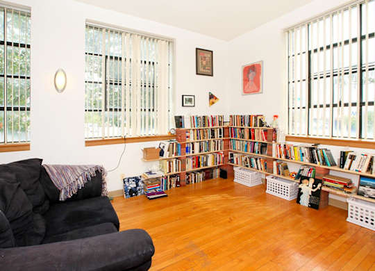 A living room with a black couch and a bookshelf filled with books.