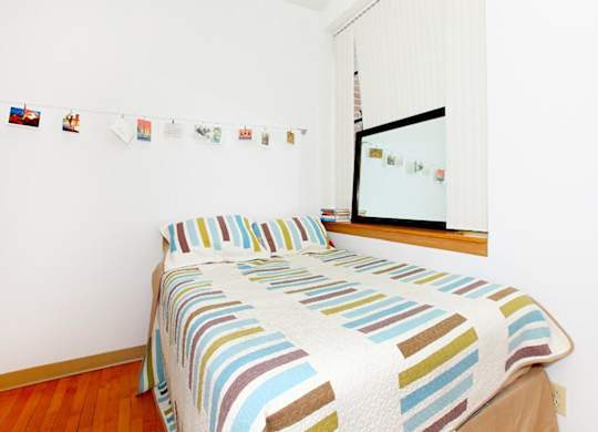 A bed with a striped comforter is in a room with a mirror and pictures on the wall.