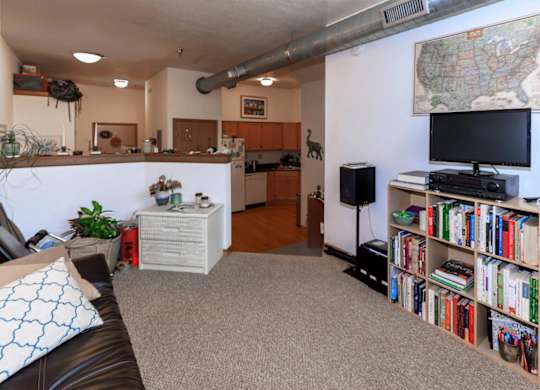 A living room with a couch, bookshelf, and a map on the wall.