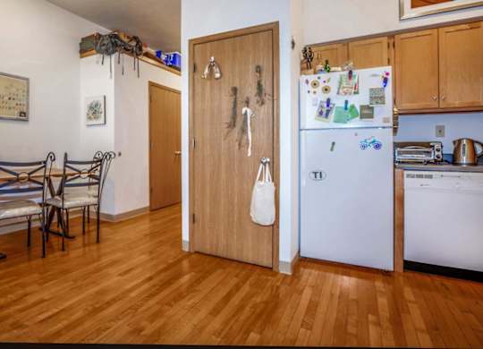 A kitchen with a white fridge and wooden floors.