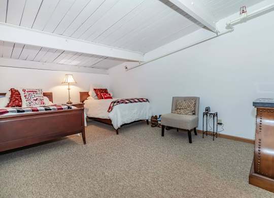 A bedroom with two beds and a chair.