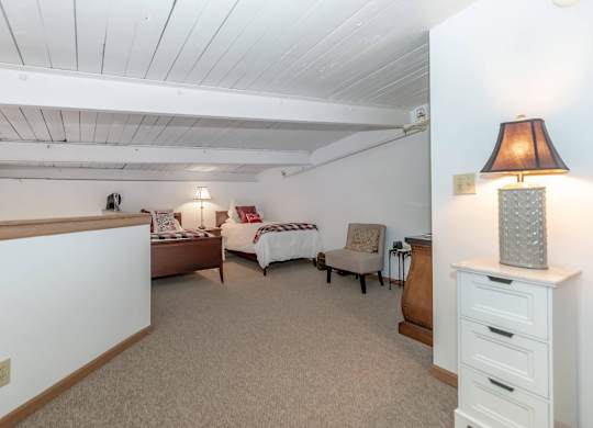 A bedroom with a bed, chair, and lamp.