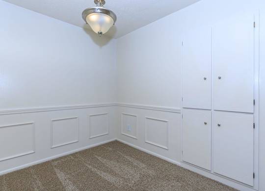 A white room with a carpeted floor and a light fixture on the ceiling.