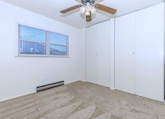 A room with a ceiling fan and carpeted floor.