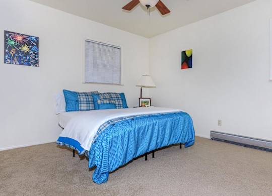A bedroom with a bed covered in a blue bedspread.