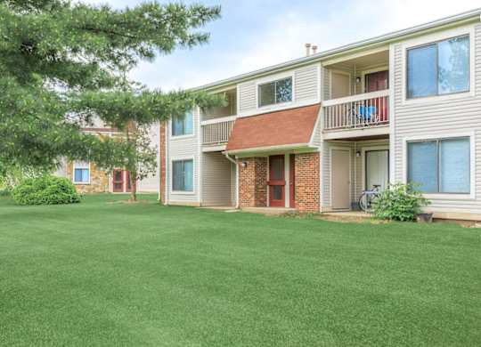 A grassy front yard in front of a two story apartment building.