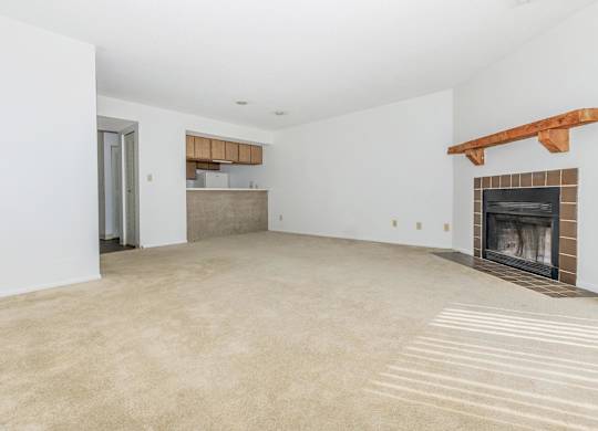 A large, empty room with a fireplace and a doorway leading to another room.
