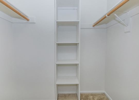 A white shelving unit with four shelves is mounted on a white wall.