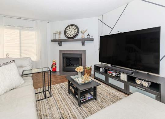 A living room with a fireplace, a sofa, a coffee table, and a television.