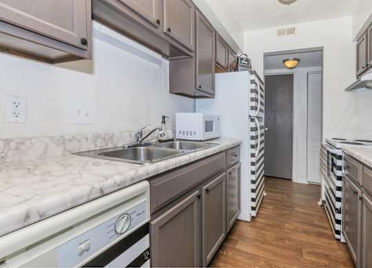 A kitchen with a white fridge and a white sink.