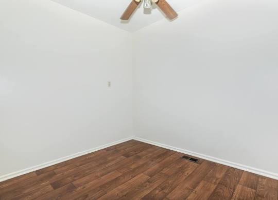 A room with a ceiling fan and wooden flooring.