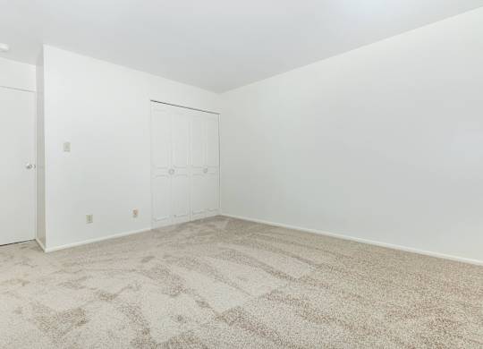 A room with a carpeted floor and two doors.