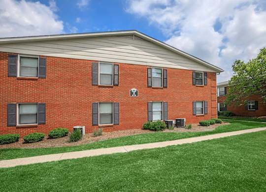 A red brick building with a white roof and a green lawn in front.