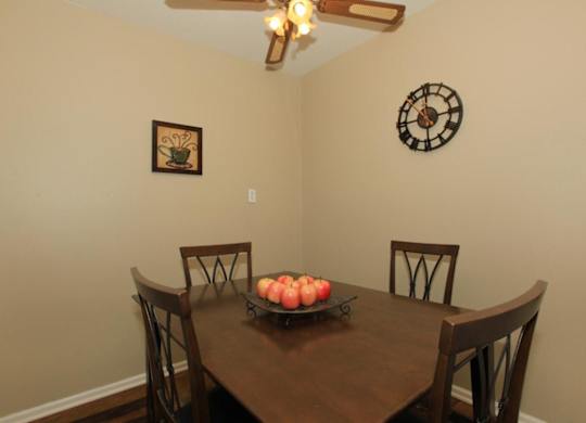 A brown table with a tray of apples on it and four chairs around it.