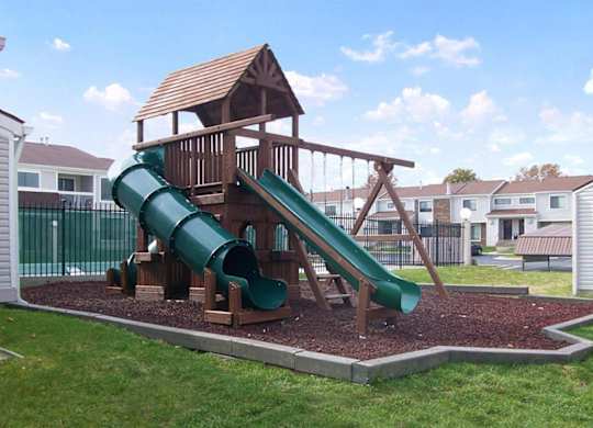 A playground with a green slide and a wooden structure.