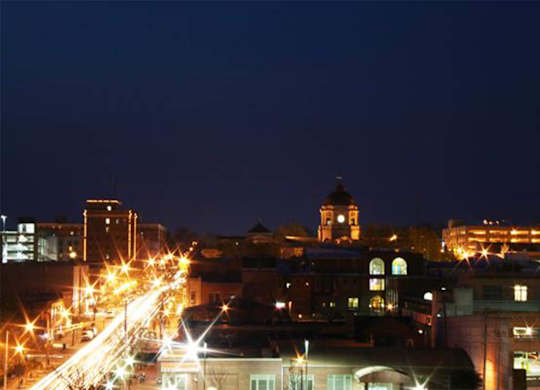 A cityscape at night with bright lights and a dark sky.