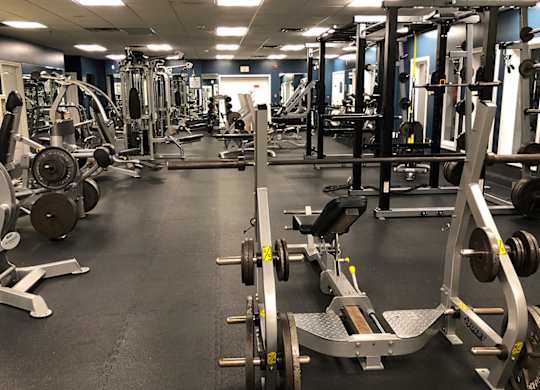 A gym with a variety of equipment including weights and weight machines.