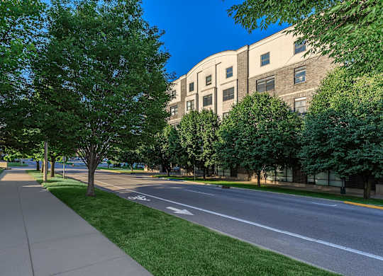 A tree-lined sidewalk runs parallel to a street.