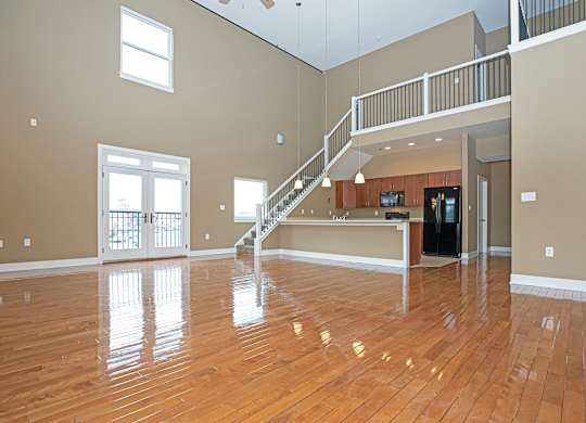 A spacious room with wooden floors and a staircase.