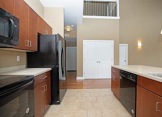 A kitchen with black appliances and brown cabinets.