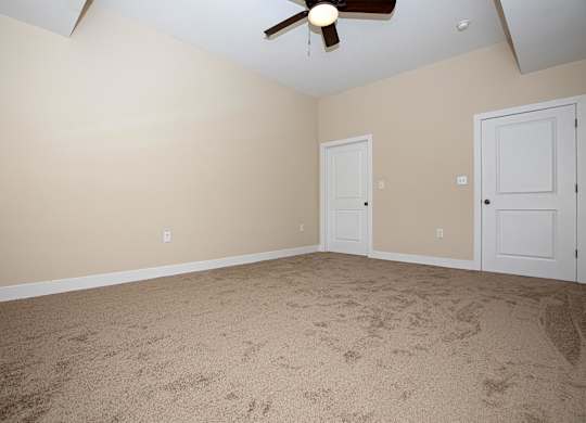 A room with a ceiling fan and two doors.