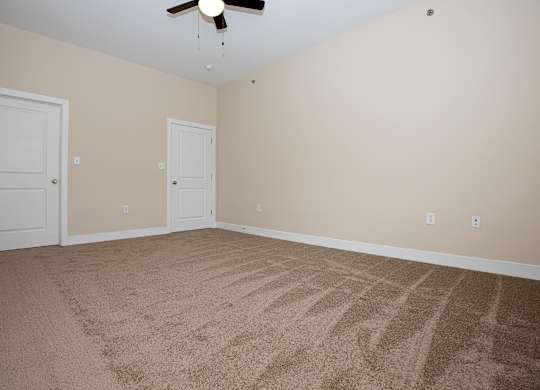 A room with a carpeted floor and a ceiling fan.