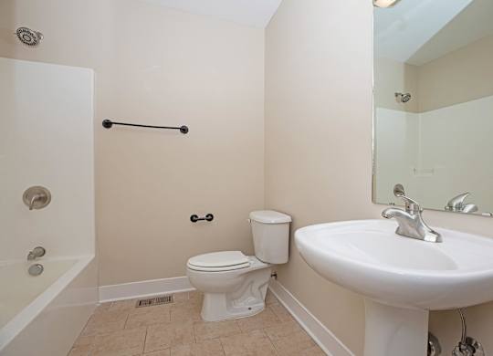 A white toilet sits next to a white sink in a bathroom.