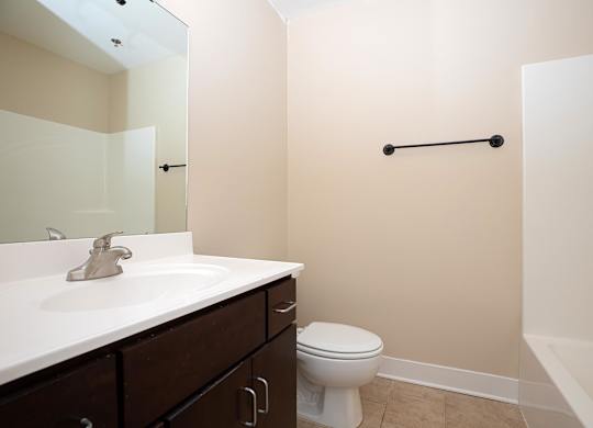A white toilet sits in a bathroom with a white sink and a white bathtub.