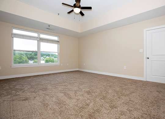 A room with a ceiling fan and carpeted floor.