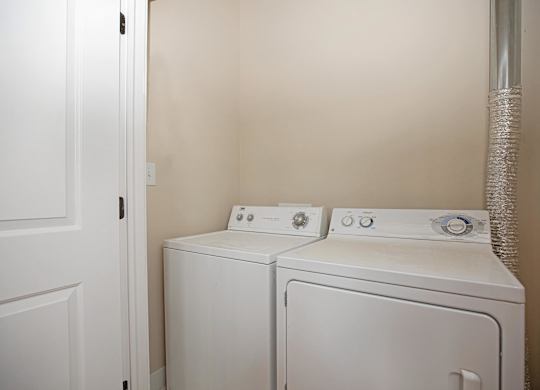 Two white washing machines in a small laundry room.