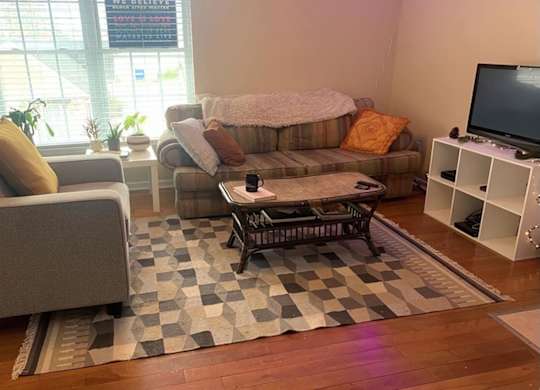 A living room with a grey couch, a brown sofa, a coffee table, and a television.