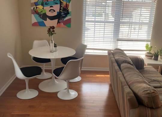 A living room with a couch, chairs, and a painting on the wall.