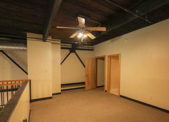 A room with a ceiling fan and a balcony.