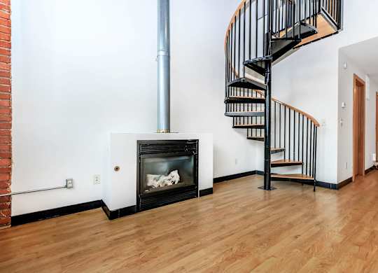 A black spiral staircase in a room with a fireplace.